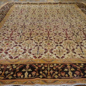 Cream and burgundy botanical rug with dark borders lies flat on a light wood floor.