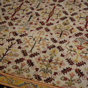 Traditional cream rug featuring dense red and yellow floral motifs and a visible gold patterned border.