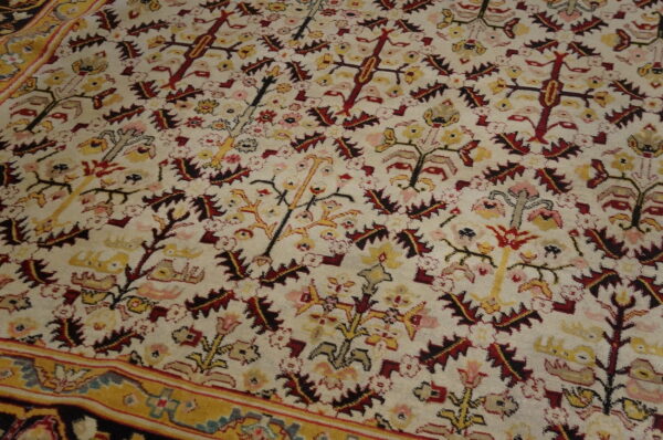 Traditional cream rug featuring dense red and yellow floral motifs and a visible gold patterned border.