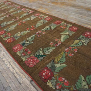 Textured brown runner rug with repetitive red and green floral garland motifs on distressed wood floors.