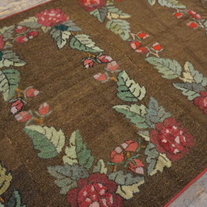 Textured brown rug featuring repeated red rose and green leaf garlands rests on wood plank flooring.