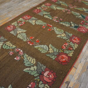 Dark brown textured runner featuring red and green floral garland patterns lies on rustic wooden floors.