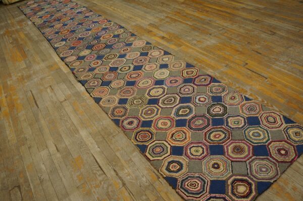 Colorful hooked runner rug featuring concentric octagons and blue squares rests on worn wood flooring.