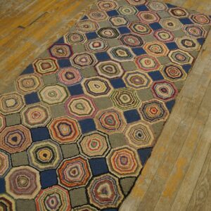 Textured runner rug patterned with multicolor concentric rings and solid blue shapes on aged wood floor.