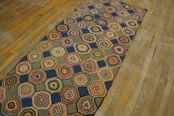 Textured runner rug patterned with multicolor concentric rings and solid blue shapes on aged wood floor.