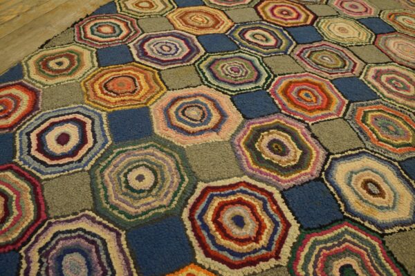 Textured rug with multicolored concentric hexagons alternating with solid blue and gray squares.