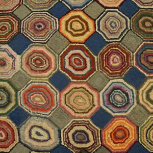Textured rug with colorful hooked octagons separated by blue and grey square shapes resting on wooden floors.