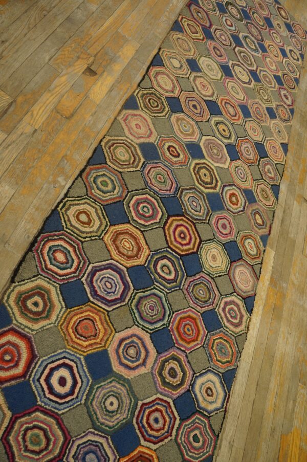 Colorful runner rug displaying concentric hexagonal patterns alternating with solid blue and sage blocks on wood flooring.