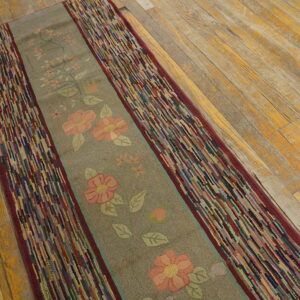 Gray floral runner with highly textured, multicolored striped borders lies diagonally on rustic wood floor.