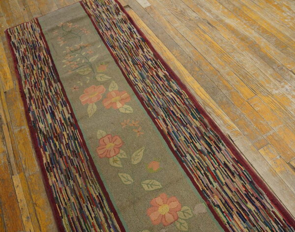 Gray floral runner with highly textured, multicolored striped borders lies diagonally on rustic wood floor.