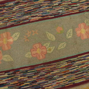 Textured rug displaying a sage floral band bordered by sections of bright multi-colored strips.