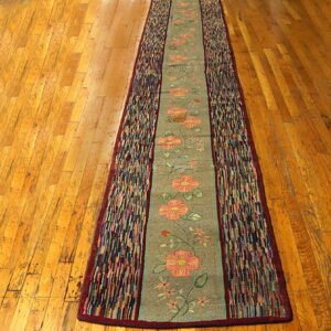 A sage floral runner with multicolored strip borders lies centered on glossy amber wood flooring.