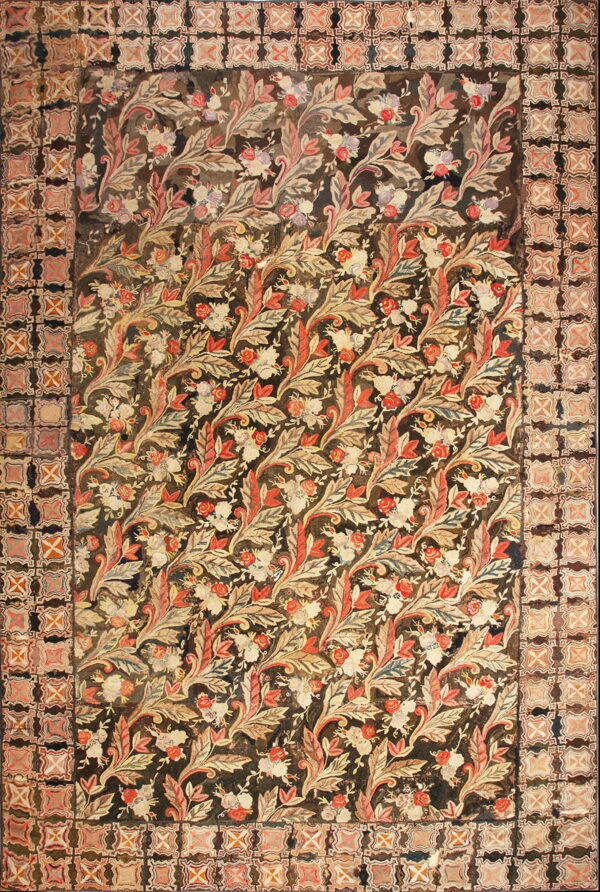 Muted red, cream, and dark brown low pile rug displaying a dense foliage pattern and geometric border.