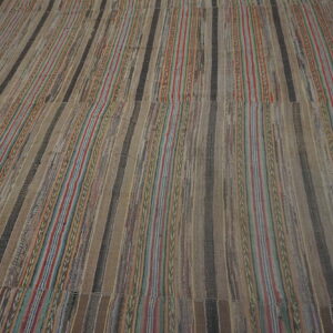 Flat-weave rug with wide neutral brown and narrow red, blue, and green vertical stripes.