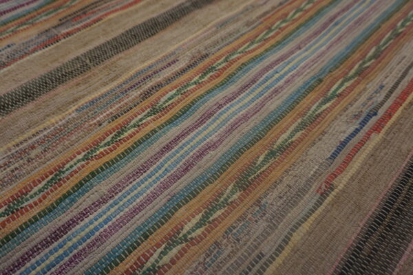 Close-up of a low-pile striped rug with woven multicolored strips in brown, blue, purple, and gray.
