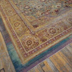 Traditional floral rug in teal, gold, and purple borders rests on worn plank hardwood flooring.