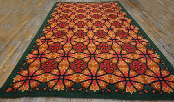 Vibrant orange and red geometric runner rug with a dark green border rests on distressed wooden flooring.