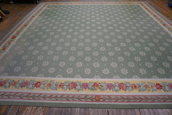 Sage green area rug featuring white scattered daisies and colorful floral borders on rustic wood flooring.