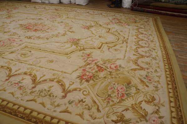 Cream rug featuring neoclassical gold scrollwork and garlands of pink and green roses on distressed wood flooring.