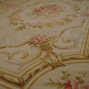 A low-pile rug featuring an ornate floral medallion and scrolling borders in gold, pink, and cream colors.