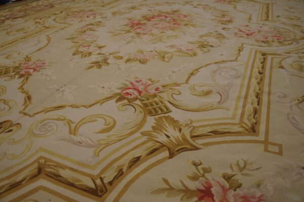 A low-pile rug featuring an ornate floral medallion and scrolling borders in gold, pink, and cream colors.