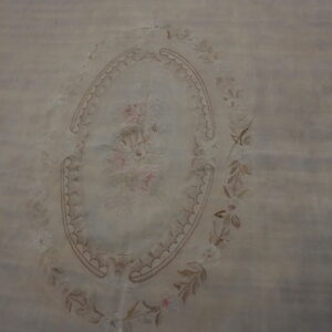 A pale beige rug with a central oval medallion featuring pink roses and surrounding floral borders.
