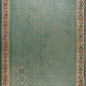 Muted teal rug with a lattice pattern and wide beige border featuring mauve and green floral motifs.