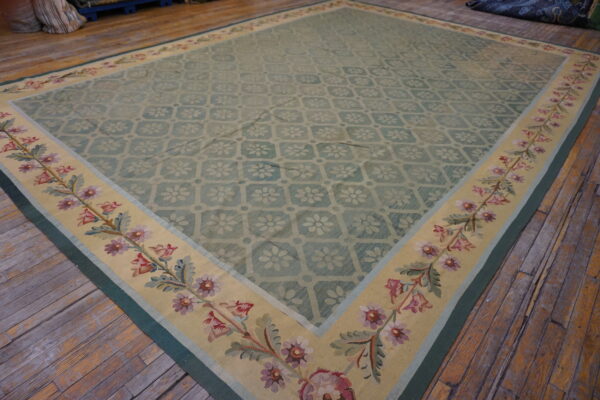 Blue-green flatweave rug with a subtle floral field pattern and a wide yellow border featuring pink and green flowers.