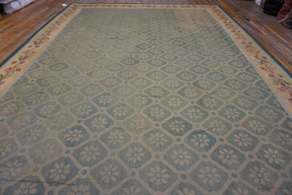 Large light blue rug with a diamond floral trellis pattern and a wide botanical border on wood flooring.