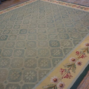 Teal and beige floral medallion rug with a wide yellow border and pink flowers, lying on wood floors.