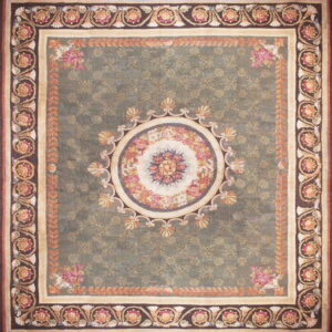 A large green rug with an ornate floral medallion center and multi-layered borders in pink, cream, and brown.