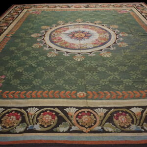 Ornate low-pile rug with a sage green field, a central floral medallion, and dark multi-color borders.