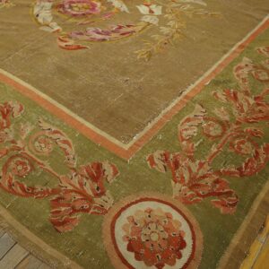 Low-pile rug in khaki and olive green with rust floral patterns, resting on wide wood planks.