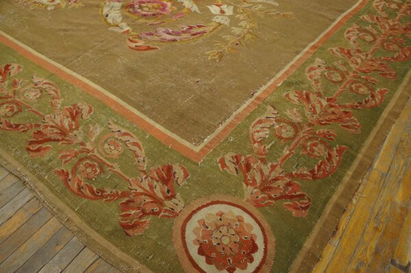 Low-pile rug in khaki and olive green with rust floral patterns, resting on wide wood planks.