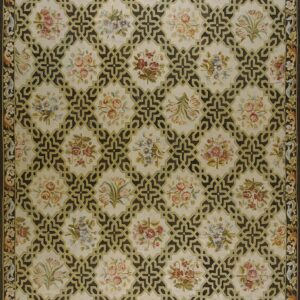 Cream rug with a repeating pattern of dark geometric trelliswork framing pale multicolored floral clusters.