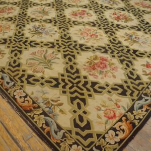 Cream and dark brown rug featuring geometric squares, colorful floral bouquets, and a decorative border on wood floors.