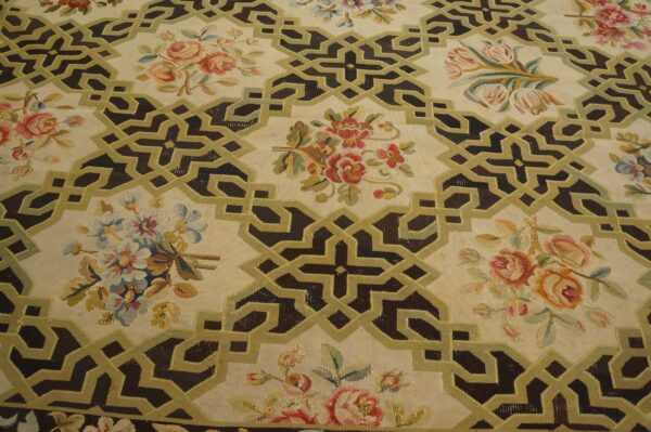 Cream rug featuring dark brown interlocking geometric patterns outlined in olive green, interspersed with colorful floral clusters.