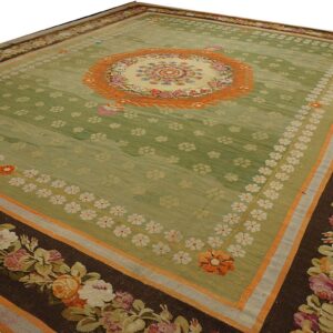 Green area rug featuring a central floral medallion and dark borders with large colorful rose garlands.