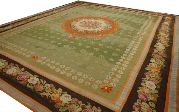 Green area rug featuring a central floral medallion and dark borders with large colorful rose garlands.