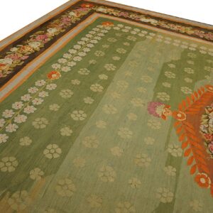 Ornate green flatweave rug displaying small floral sprays and a dark brown border of colorful roses.