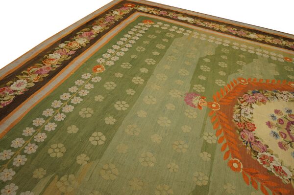 Ornate green flatweave rug displaying small floral sprays and a dark brown border of colorful roses.