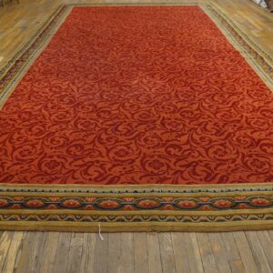 Long red rug with a tone-on-tone scrolling pattern and complex olive-and-blue border on wood floors.