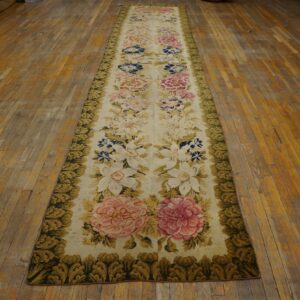 Ivory floral runner rug with pink and blue flowers and a dense green border on distressed hardwood floor.