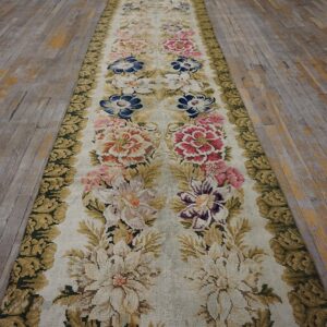 Textured runner with multicolor botanical design and olive green trim laid over distressed gray floorboards.