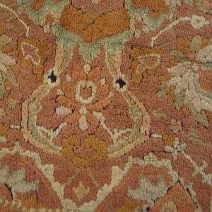 Rustic high-pile rug detailed with a traditional pattern in terracotta, muted gold, and pale green.