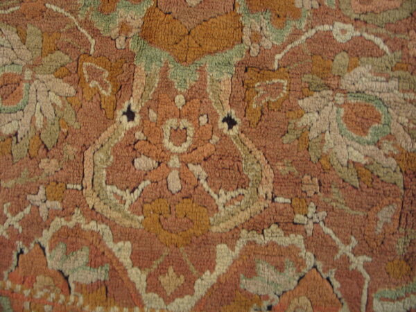 Rustic high-pile rug detailed with a traditional pattern in terracotta, muted gold, and pale green.