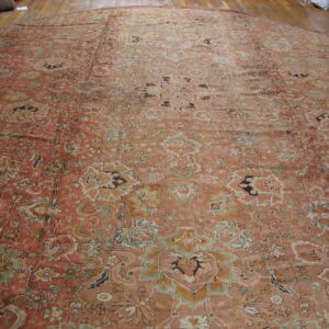 Faded salmon rug featuring an intricate all-over medallion design on a polished wooden floor.
