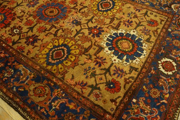 Traditional floral medallion rug in gold, navy, and red rests partially on light wood flooring.