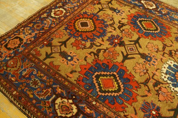Traditional rug with complex red, blue, and tan stylized floral patterns rests on light wood planks.