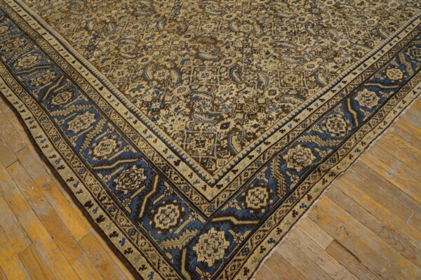 An intricate, low-pile traditional rug in beige, brown, and blue rests on distressed wooden floorboards.